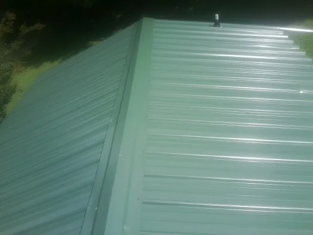 New green metal panels meeting at the ridge of a roof — Flat Roof Repair work by our crew in Beverly