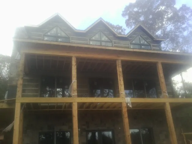 Dormers and porch framing on a large log home under construction — Roof Coating work by our crew in Beverly