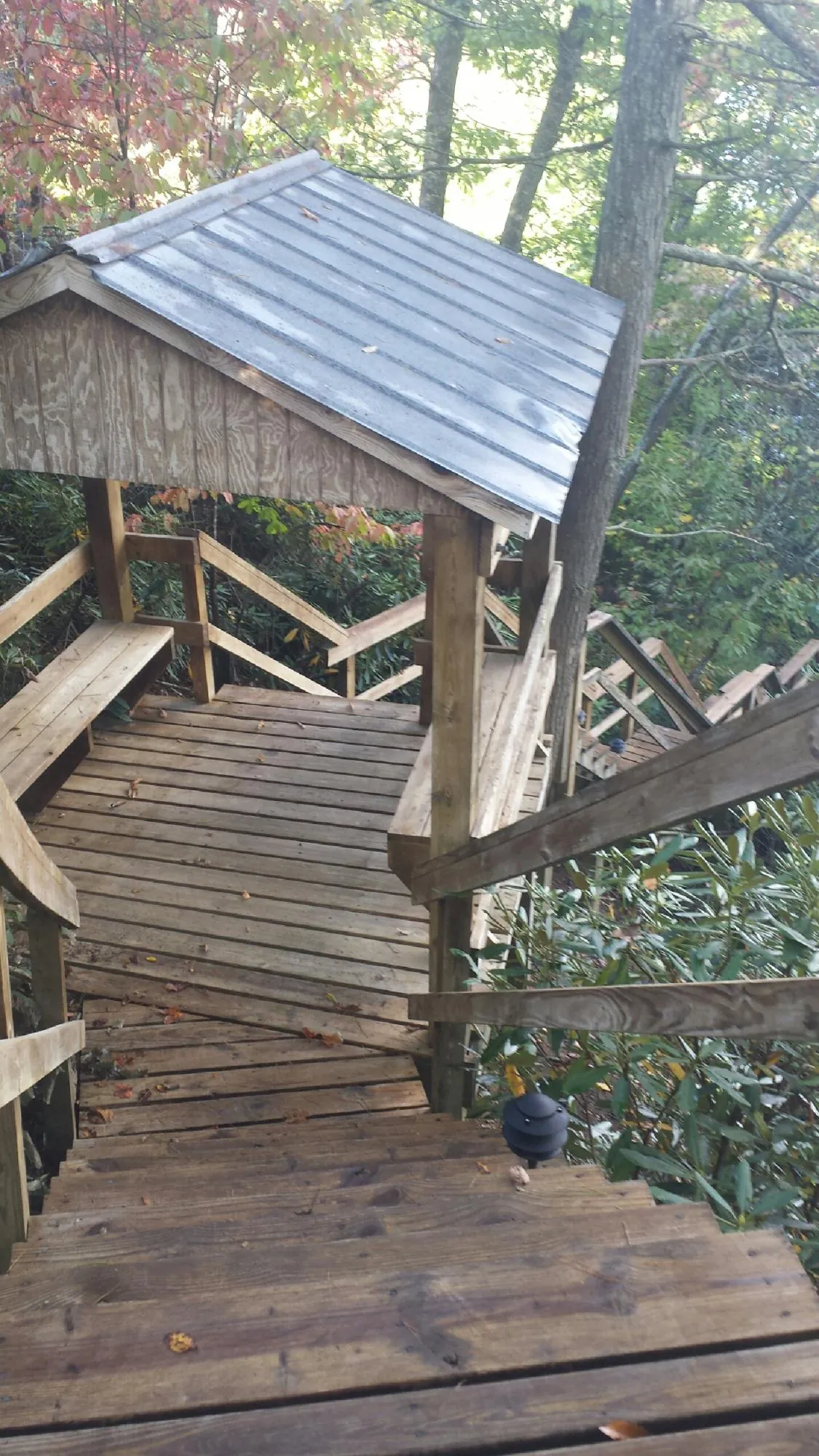 Metal roofed shelter over wooden steps on a wooded walkway — Skylight Repair & Installation work by our crew in Beverly